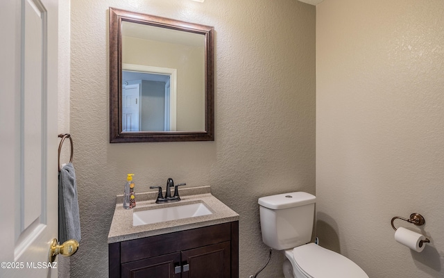 half bath with a textured wall, toilet, and vanity