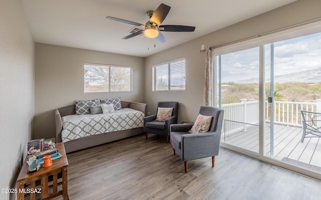 bedroom with multiple windows, access to exterior, wood finished floors, and a ceiling fan