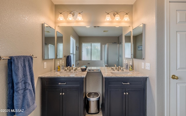 bathroom featuring a stall shower, a sink, and two vanities