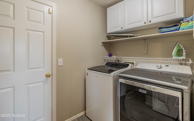 laundry area with baseboards, cabinet space, a textured wall, and washer and clothes dryer