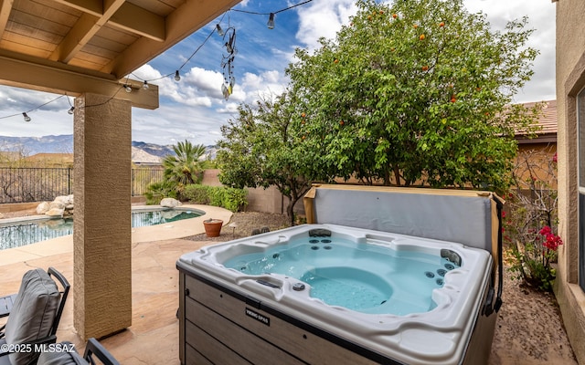 view of patio / terrace featuring a hot tub, a mountain view, a fenced backyard, and a fenced in pool