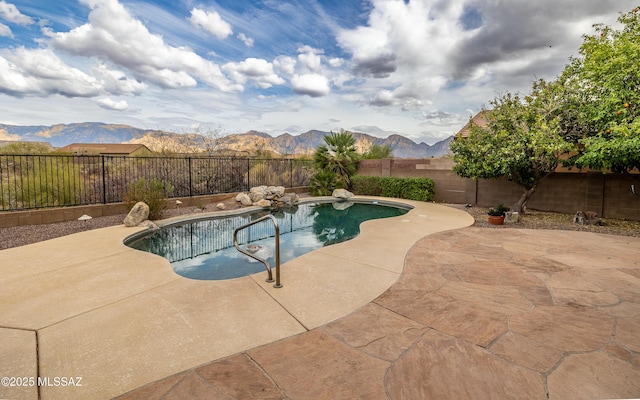 view of swimming pool featuring a mountain view, a fenced backyard, a fenced in pool, and a patio area