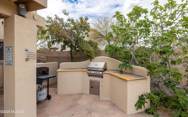 view of patio with grilling area, exterior kitchen, and fence