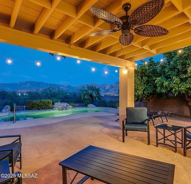 view of patio with a ceiling fan, a fenced in pool, a mountain view, and fence
