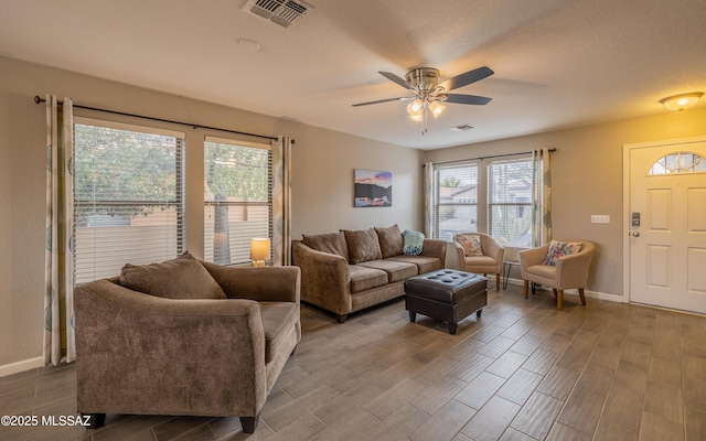 living room featuring baseboards, wood tiled floor, visible vents, and a ceiling fan