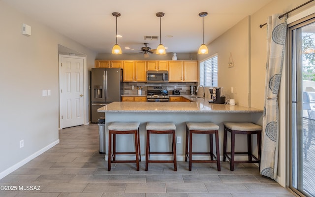 kitchen featuring a sink, tasteful backsplash, a peninsula, stainless steel appliances, and visible vents