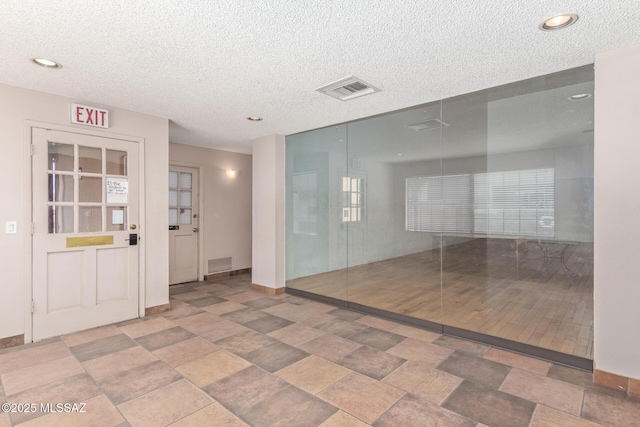unfurnished room featuring visible vents, a textured ceiling, and baseboards