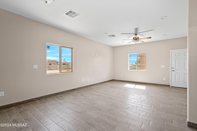empty room with a ceiling fan, plenty of natural light, and visible vents