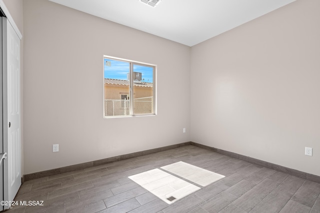 spare room featuring visible vents, baseboards, and wood finished floors