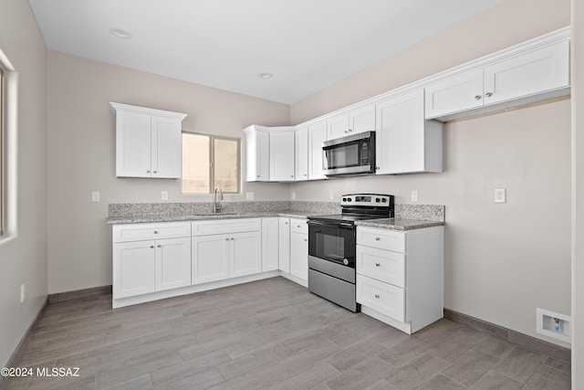 kitchen featuring white cabinets, baseboards, light stone countertops, appliances with stainless steel finishes, and a sink