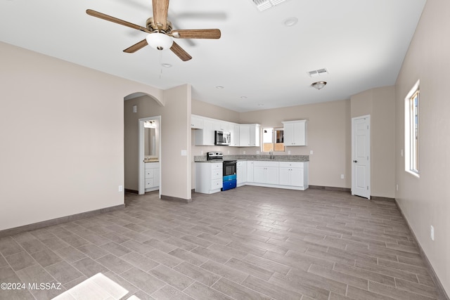 kitchen with a ceiling fan, electric range oven, stainless steel microwave, visible vents, and arched walkways