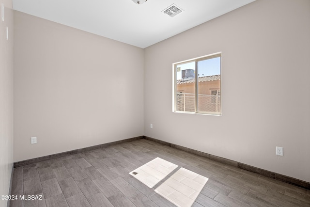 empty room with wood finished floors, baseboards, and visible vents