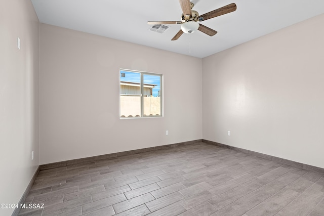 spare room with baseboards, ceiling fan, visible vents, and wood finished floors