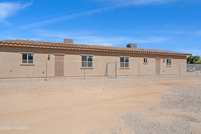 back of house with a tile roof, a fenced front yard, and a chimney