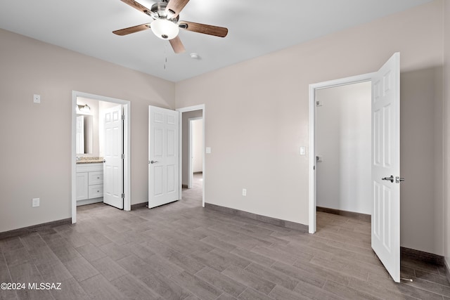 unfurnished bedroom featuring baseboards, ensuite bathroom, wood finished floors, and a ceiling fan