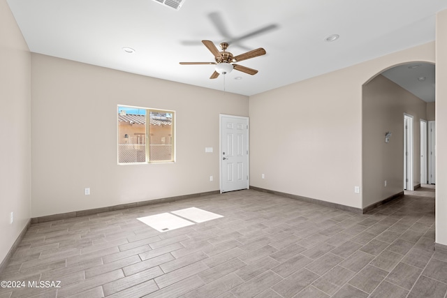 spare room featuring baseboards, wood finished floors, recessed lighting, a ceiling fan, and arched walkways