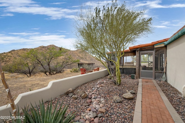 view of yard featuring fence, a sunroom, and a mountain view