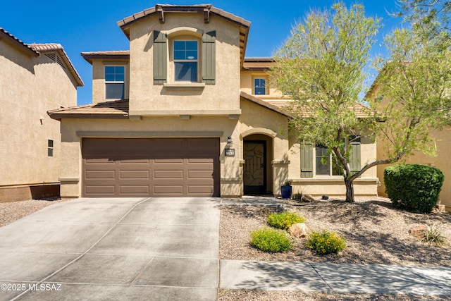 mediterranean / spanish home with a garage, stucco siding, driveway, and a tiled roof