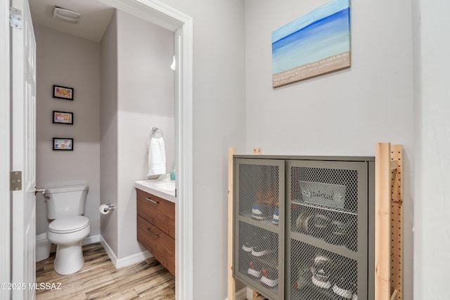 bathroom featuring baseboards, vanity, toilet, and wood finished floors