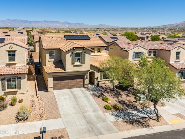 mediterranean / spanish home with a garage, stucco siding, a tiled roof, concrete driveway, and a residential view