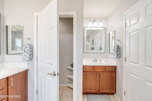 full bathroom with a sink, baseboards, tile patterned flooring, and two vanities