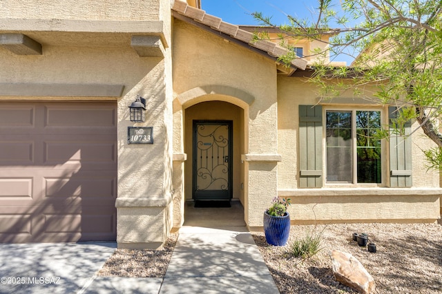 doorway to property with a garage and stucco siding