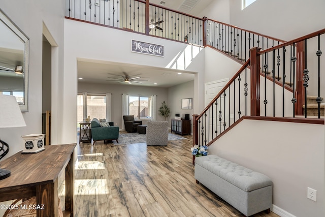 interior space featuring a high ceiling, stairs, ceiling fan, and wood finished floors