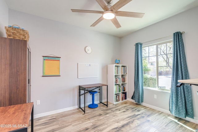 interior space featuring baseboards, a ceiling fan, and wood finished floors