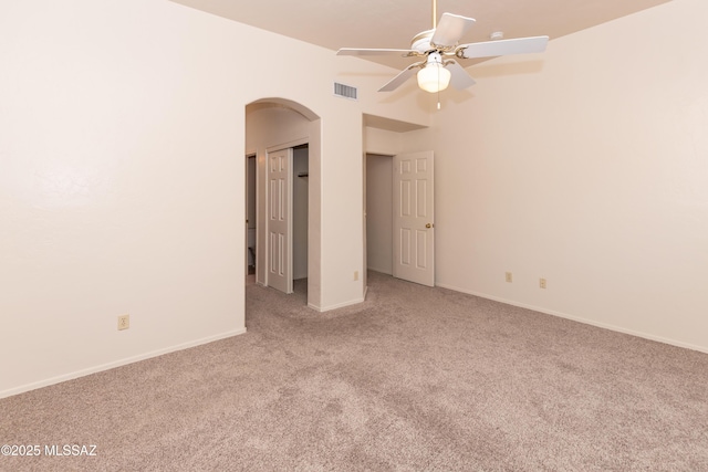 spare room with visible vents, carpet, baseboards, a ceiling fan, and arched walkways