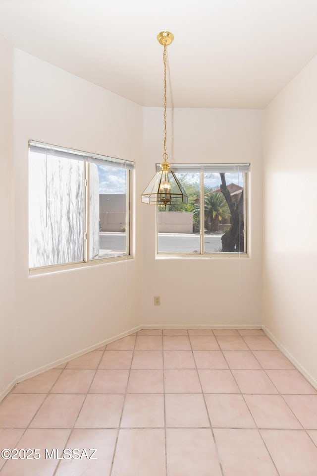 empty room with plenty of natural light, baseboards, and light tile patterned flooring