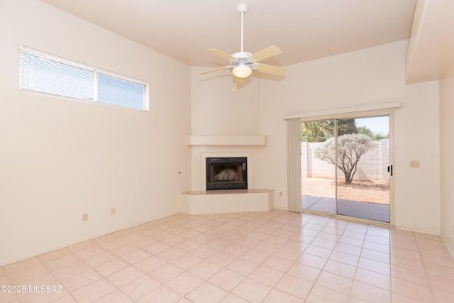unfurnished living room featuring a fireplace with raised hearth, light tile patterned floors, and a ceiling fan