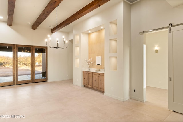 unfurnished dining area featuring beam ceiling, a barn door, baseboards, an inviting chandelier, and light tile patterned flooring
