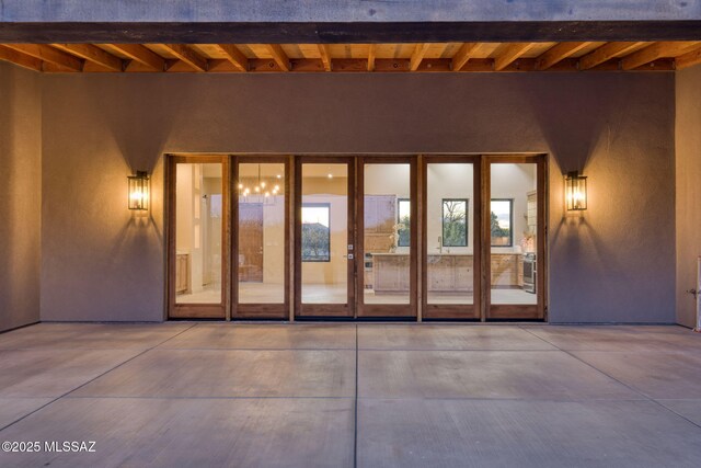 view of exterior entry with a patio and stucco siding