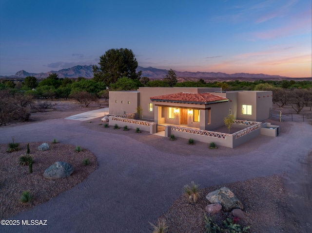 view of front of house featuring fence, a mountain view, stucco siding, and dirt driveway