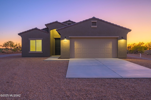 single story home with a garage, stucco siding, a tile roof, and concrete driveway