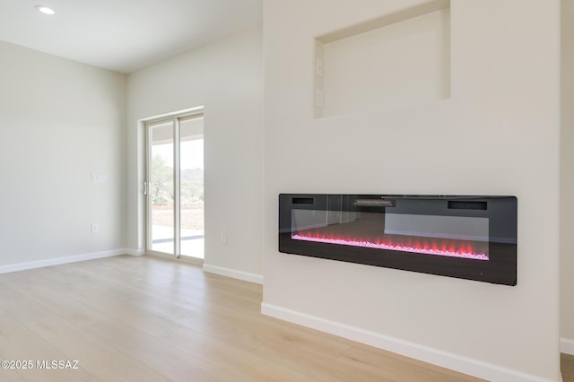 room details featuring a glass covered fireplace, baseboards, recessed lighting, and wood finished floors