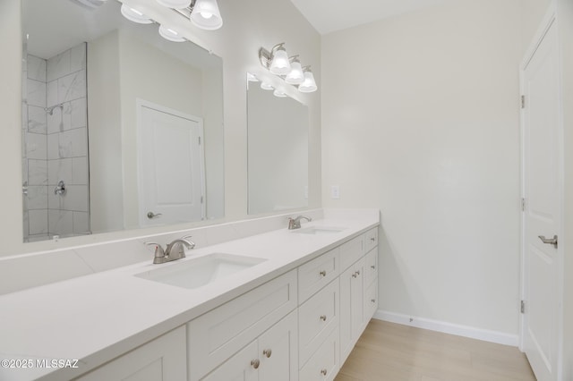 bathroom with double vanity, a sink, baseboards, and wood finished floors