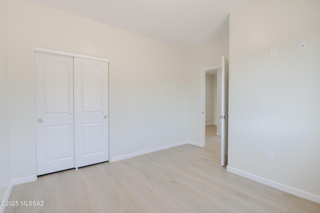 unfurnished bedroom featuring a closet, baseboards, and light wood-type flooring