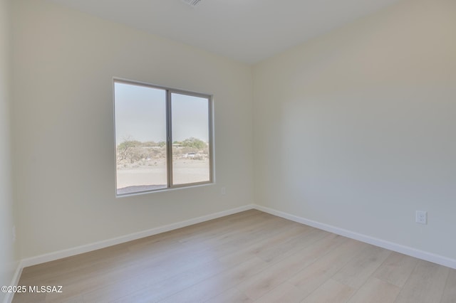 spare room featuring baseboards and light wood finished floors