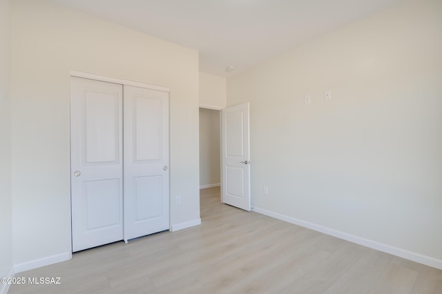 unfurnished bedroom featuring baseboards, a closet, and light wood finished floors