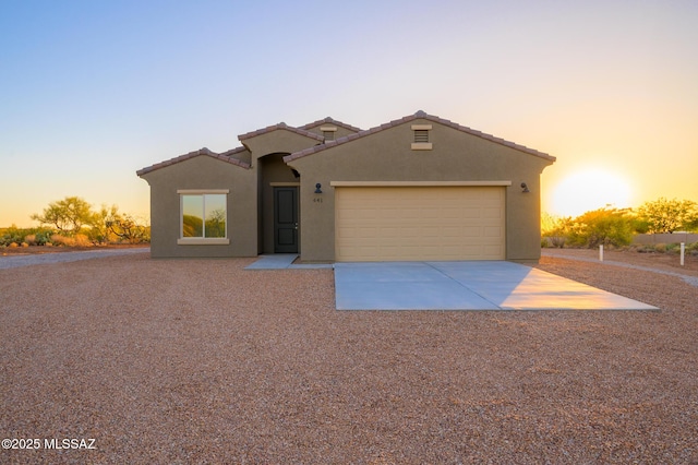 view of front of house featuring an attached garage, stucco siding, driveway, and a tile roof