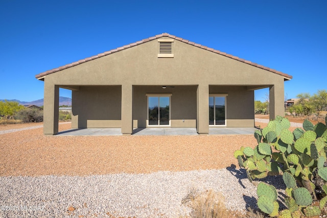 rear view of house featuring a patio, a mountain view, and stucco siding
