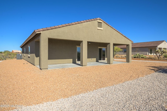 rear view of property with a patio, stucco siding, a tile roof, and cooling unit