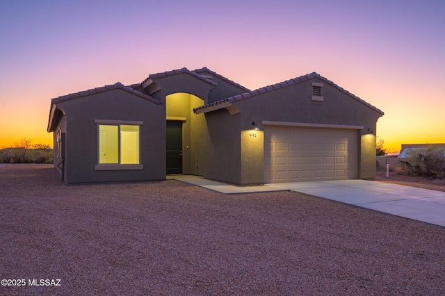 ranch-style house featuring an attached garage, stucco siding, driveway, and a tiled roof