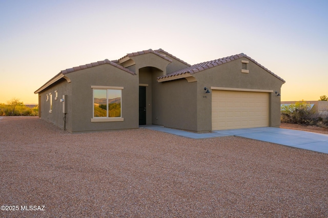 view of front of home with a garage, stucco siding, concrete driveway, and a tile roof
