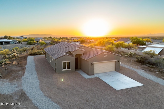 view of front of property with a garage, stucco siding, driveway, and a tiled roof
