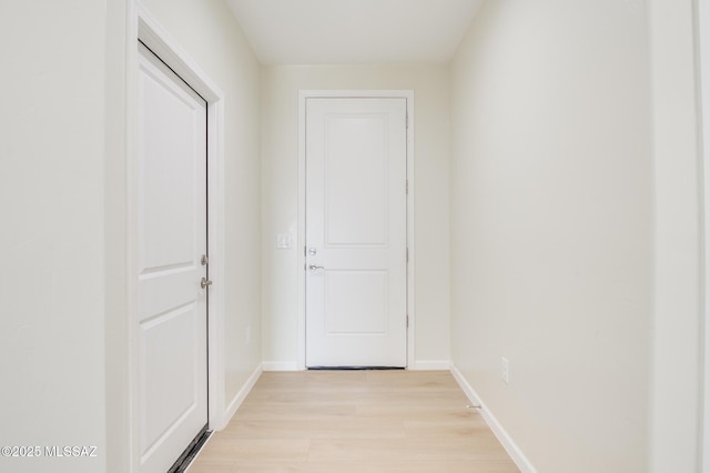 corridor featuring baseboards and light wood-type flooring