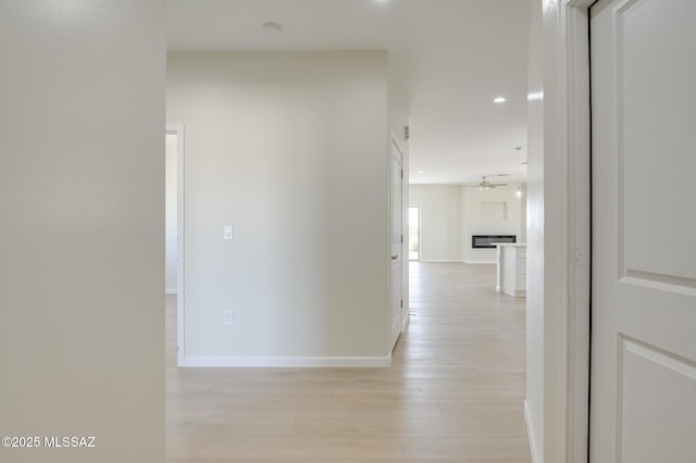 hallway featuring recessed lighting, baseboards, and light wood finished floors