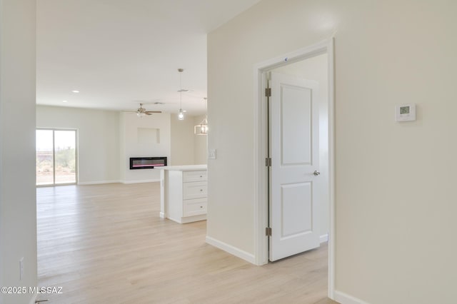 hallway with light wood-type flooring, recessed lighting, and baseboards