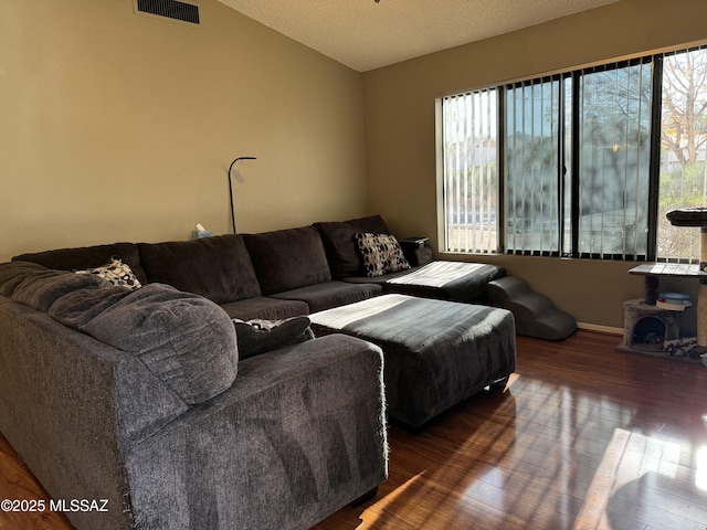living area featuring a textured ceiling, wood finished floors, visible vents, and lofted ceiling